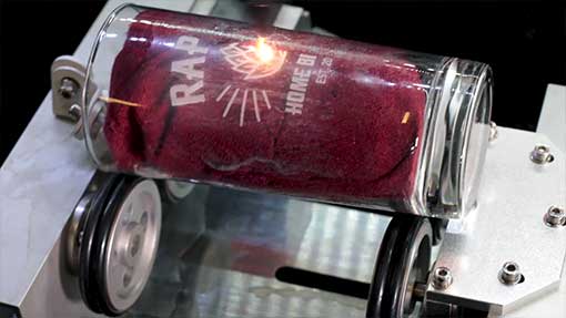A clear glass jar with a red fabric inside, being laser-engraved
