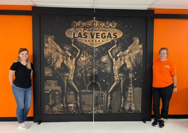 A wooden door intricately engraved with a detailed depiction of Las Vegas showgirls, created using AP Lazer’s precision laser engraving technology.